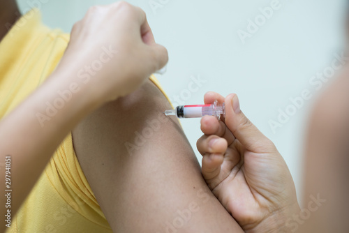 Close up doctor s hand injecting for vaccine in the shoulder woman patient.Nurse using syringe are vaccination to patient for influenza protection.Medication treatment concept.