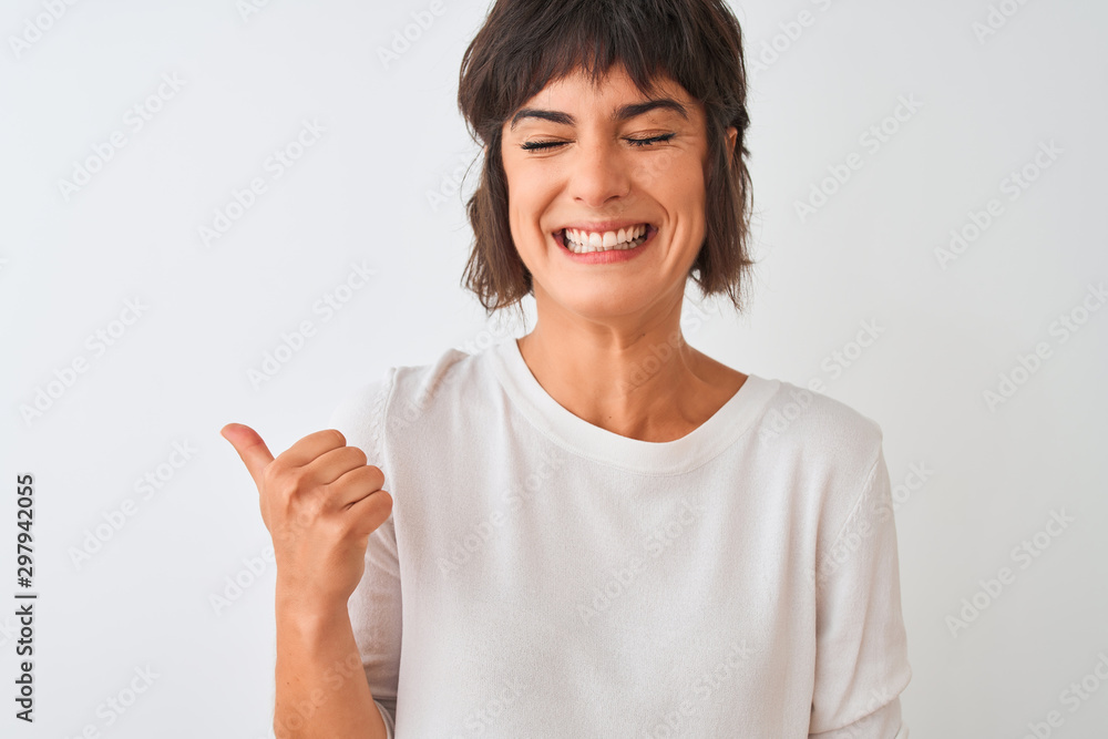 Young beautiful woman wearing casual t-shirt standing over isolated white background pointing and showing with thumb up to the side with happy face smiling Young beautiful woman wearing casual t-shirt standing over isolated white background pointing and showing with thumb up to the side with happy face smiling
