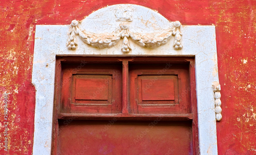 Old red portal with relief decorations, architecture detail in an old romantic Latino district.
