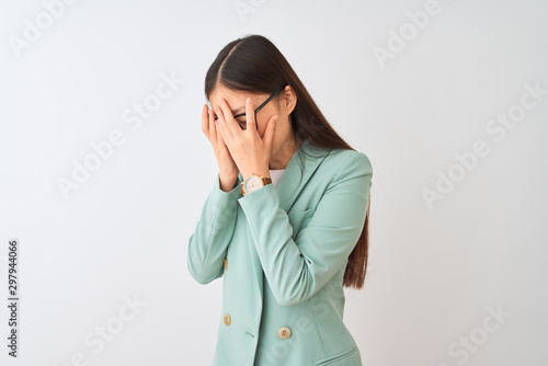 Chinese businesswoman wearing elegant jacket and glasses over isolated white background with sad expression covering face with hands while crying. Depression concept.