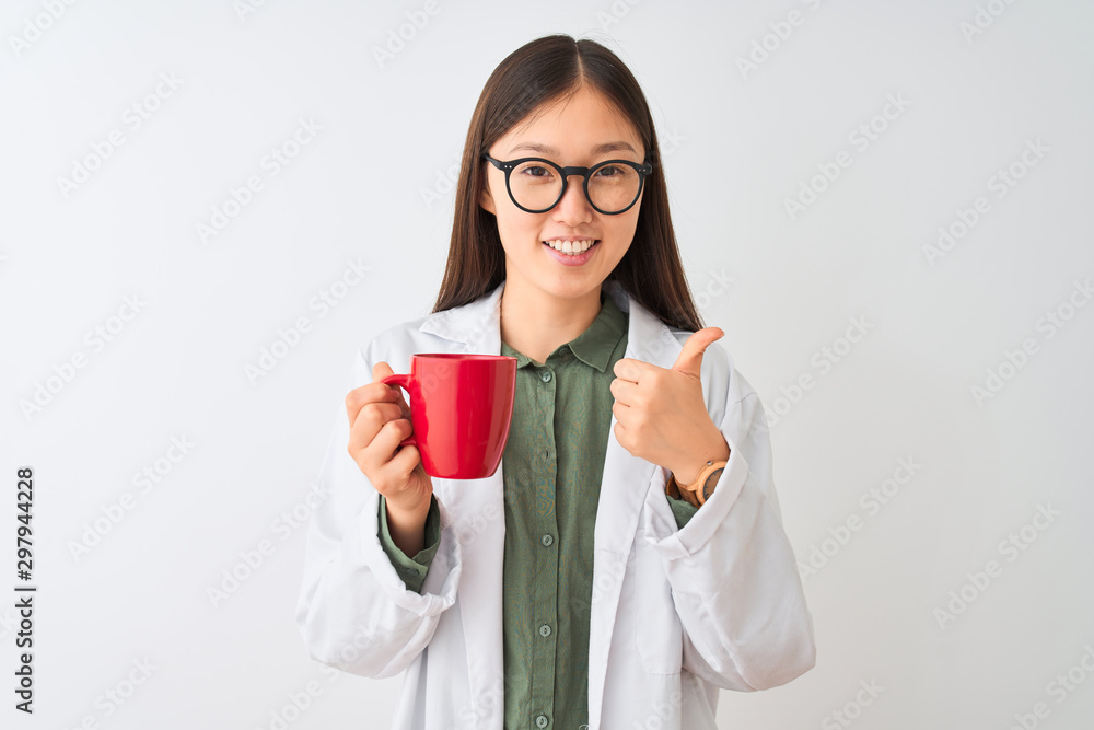 Young chinese dooctor woman wearing glasses drinking coffee over isolated white background happy with big smile doing ok sign, thumb up with fingers, excellent sign Young chinese dooctor woman wearing glasses drinking coffee over isolated white background happy with big smile doing ok sign, thumb up with fingers, excellent sign
