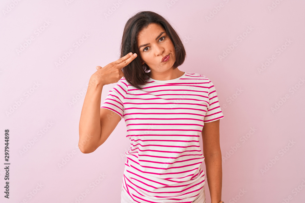 Young beautiful woman wearing striped t-shirt standing over isolated pink background Shooting and killing oneself pointing hand and fingers to head like gun, suicide gesture. Young beautiful woman wearing striped t-shirt standing over isolated pink background Shooting and killing oneself pointing hand and fingers to head like gun, suicide gesture.