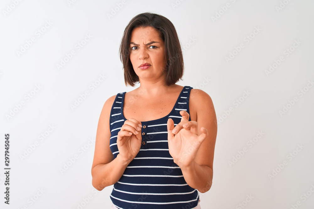 Young beautiful woman wearing blue striped t-shirt standing over isolated white background disgusted expression, displeased and fearful doing disgust face because aversion reaction. With hands raised Young beautiful woman wearing blue striped t-shirt standing over isolated white background disgusted expression, displeased and fearful doing disgust face because aversion reaction. With hands raised