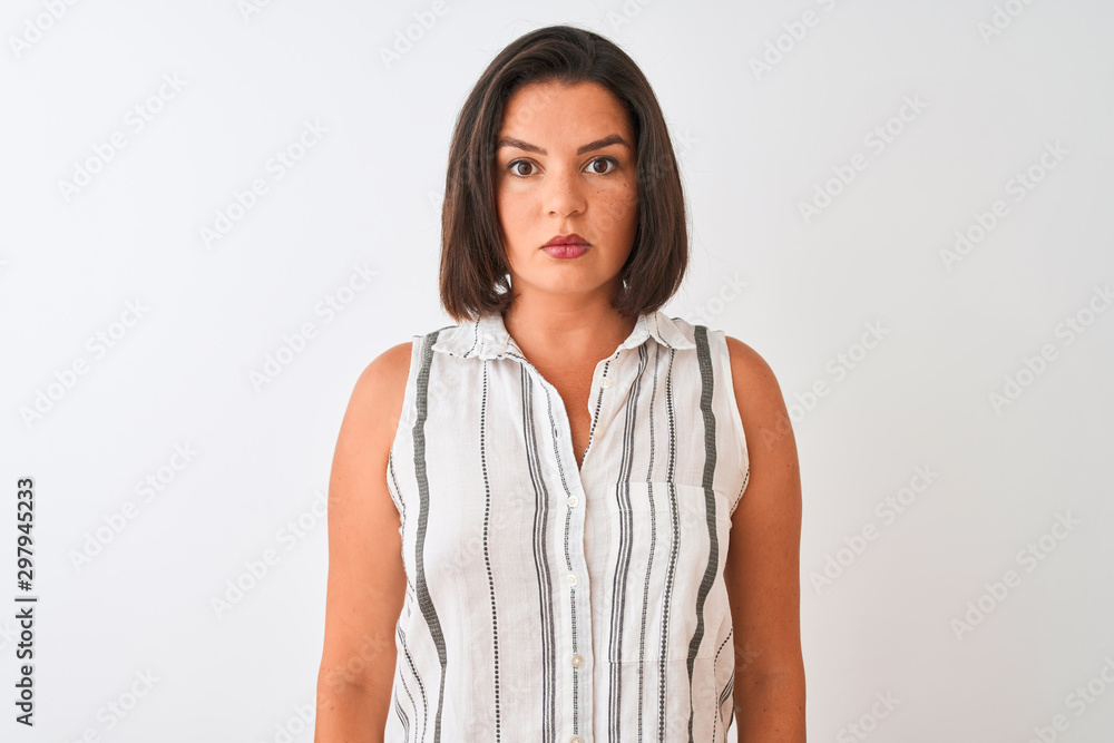 Young beautiful woman wearing casual striped shirt standing over isolated white background with serious expression on face. Simple and natural looking at the camera. Young beautiful woman wearing casual striped shirt standing over isolated white background with serious expression on face. Simple and natural looking at the camera.