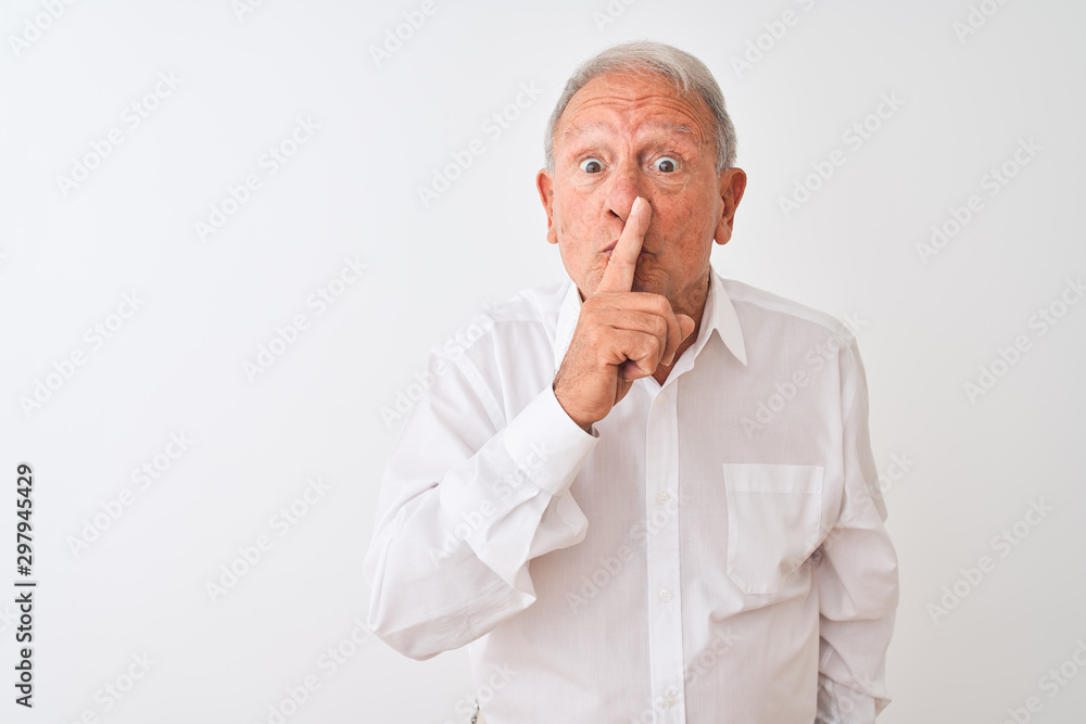 Senior grey-haired man wearing elegant shirt standing over isolated white background asking to be quiet with finger on lips. Silence and secret concept. Senior grey-haired man wearing elegant shirt standing over isolated white background asking to be quiet with finger on lips. Silence and secret concept.