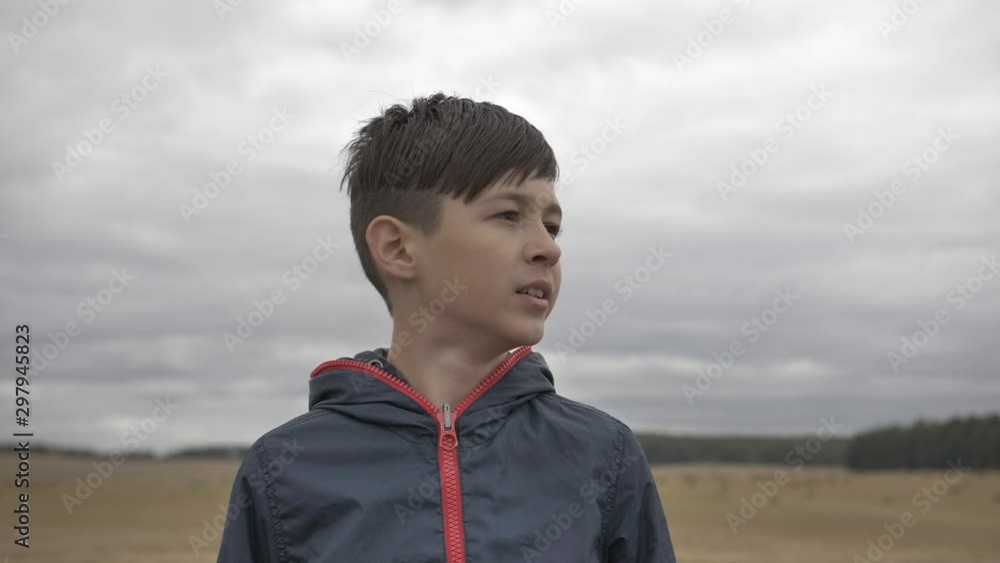 boy stands in a field outdoors and yawns boy stands in a field outdoors and yawns