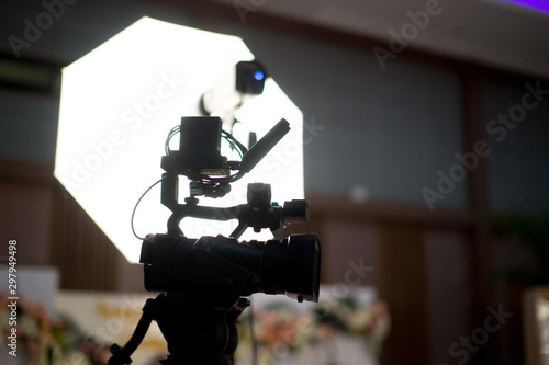 Modern digital television or video camera, camcorder, recorder in studio on blurred colorful background. Broadcasting, media, entertainment