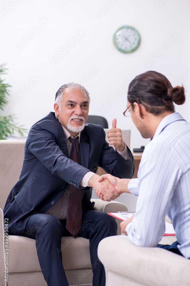 Old man visiting young male doctor psychologist Old man visiting young male doctor psychologist