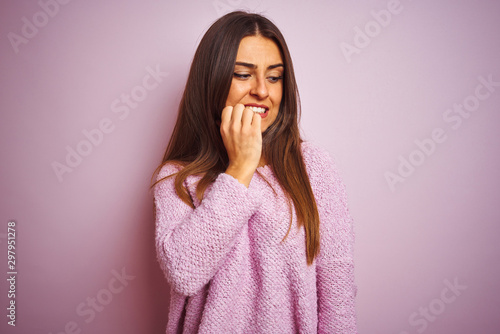 Young beautiful woman wearing casual sweater standing over isolated pink background looking stressed and nervous with hands on mouth biting nails. Anxiety problem.