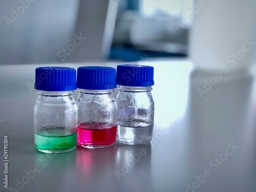 Bottles and blue cap with green, red and clear solution buffer pH 4, 7 and 10 on bench laboratory for analysis and calibrate the instrument. Blur background, has space can use for science background.