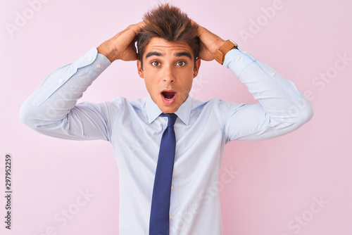 Young handsome businessman wearing shirt and tie standing over isolated pink background Crazy and scared with hands on head, afraid and surprised of shock with open mouth