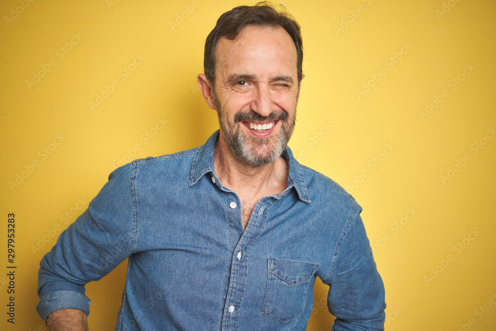 Handsome middle age senior man with grey hair over isolated yellow background winking looking at the camera with sexy expression, cheerful and happy face. Handsome middle age senior man with grey hair over isolated yellow background winking looking at the camera with sexy expression, cheerful and happy face.