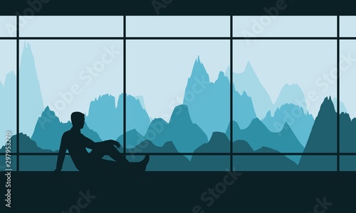 Man resting by the window with a view of the mountains. Silhouette of relaxed young man lying on the floor and dreaming at his future.