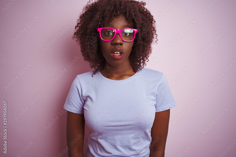 Young african afro woman wearing t-shirt glasses over isolated pink background afraid and shocked with surprise expression, fear and excited face.