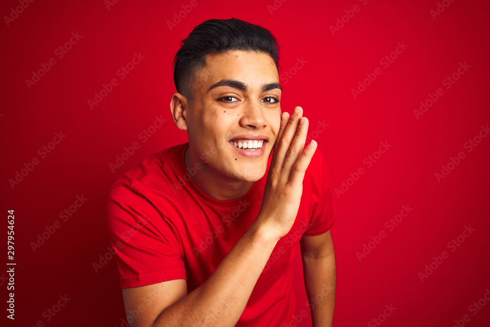 Young brazilian man wearing t-shirt standing over isolated red background hand on mouth telling secret rumor, whispering malicious talk conversation Young brazilian man wearing t-shirt standing over isolated red background hand on mouth telling secret rumor, whispering malicious talk conversation