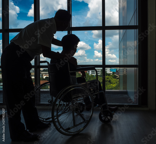 Silhouette: Father is caring for a sick person in a wheelchair by a window that has caused a trip and has insurance. photo