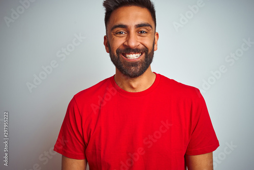 Young indian man wearing red t-shirt over isolated white background with a happy and cool smile on face. Lucky person.