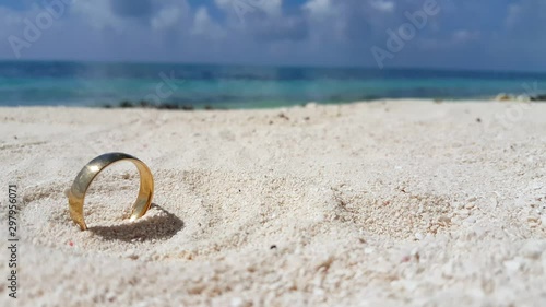 single wedding ring lost in the sand of the white tropical beach. Cheating on the business trip concept photo