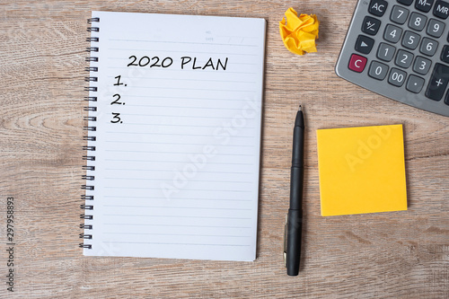 2020 NEW YEAR PLAN word on note with pen and crumbled paper on wooden table background. NEW START, Strategy and Goal concept