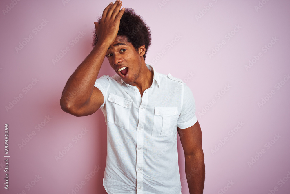 Young american man with afro hair wearing white shirt standing over isolated pink background surprised with hand on head for mistake, remember error. Forgot, bad memory concept. Young american man with afro hair wearing white shirt standing over isolated pink background surprised with hand on head for mistake, remember error. Forgot, bad memory concept.
