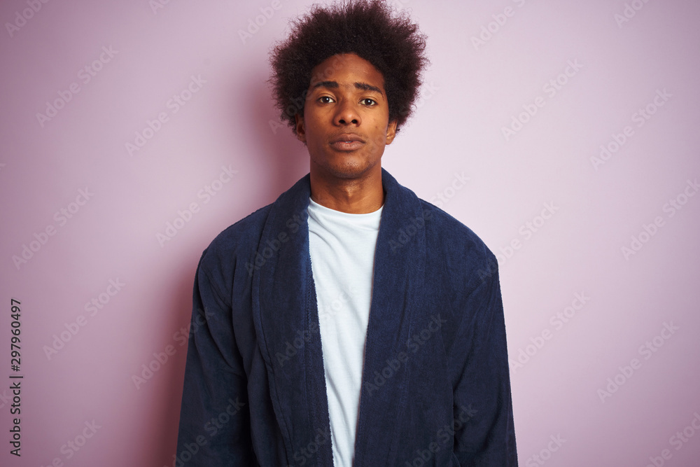 Fototapeta premium Young african american man wearing pajama standing over isolated pink background with serious expression on face. Simple and natural looking at the camera.