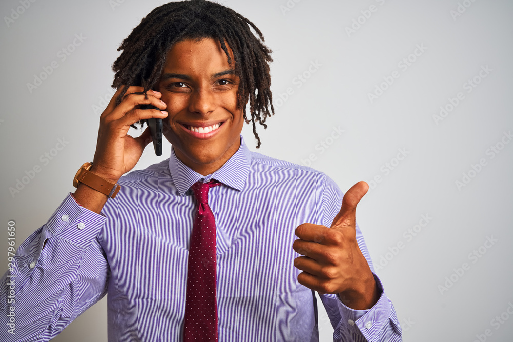 Afro businessman with dreadlocks talking using smartphone over isolated white background happy with big smile doing ok sign, thumb up with fingers, excellent sign