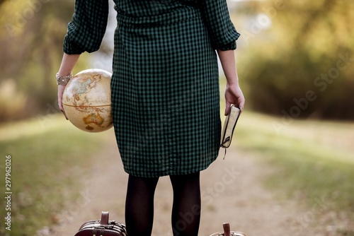 Female holding a desk globe and the bible while standing on empty pathway with blurred background photo
