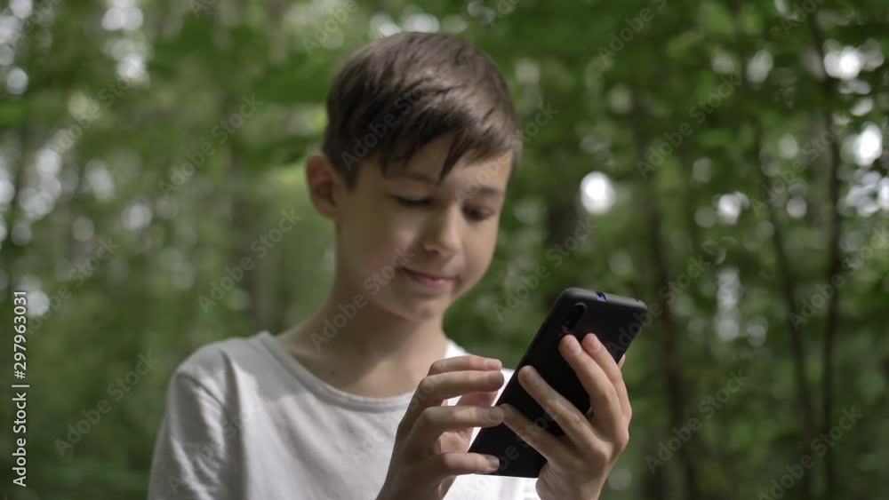 boy walking in the forest and uses a phone outdoors have fun boy walking in the forest and uses a phone outdoors have fun