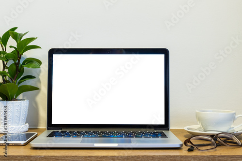 Laptop computer with blank screen with smart phone, spectacles and a coffee cup on brick wall on wooden table interior of room room hotel background,Work business in leisure with travel holiday