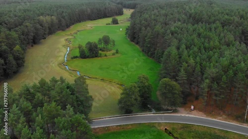 Aerial shot of an empty road between trees going across glacial valley and small creek in wdzydze kiszewskie, poland. photo