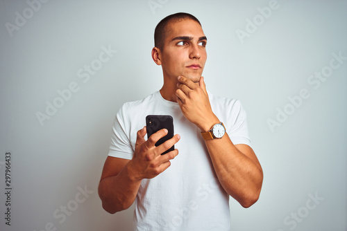 Young handsome man using smartphone over yellow isolated background serious face thinking about question, very confused idea © Krakenimages.com