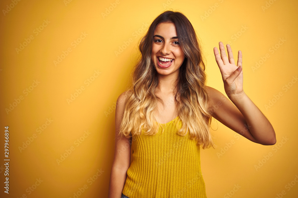 Young beautiful woman wearing t-shirt over yellow isolated background showing and pointing up with fingers number four while smiling confident and happy. Young beautiful woman wearing t-shirt over yellow isolated background showing and pointing up with fingers number four while smiling confident and happy.