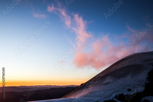 Mountain top covered by snow mear purple clouds a sunset.