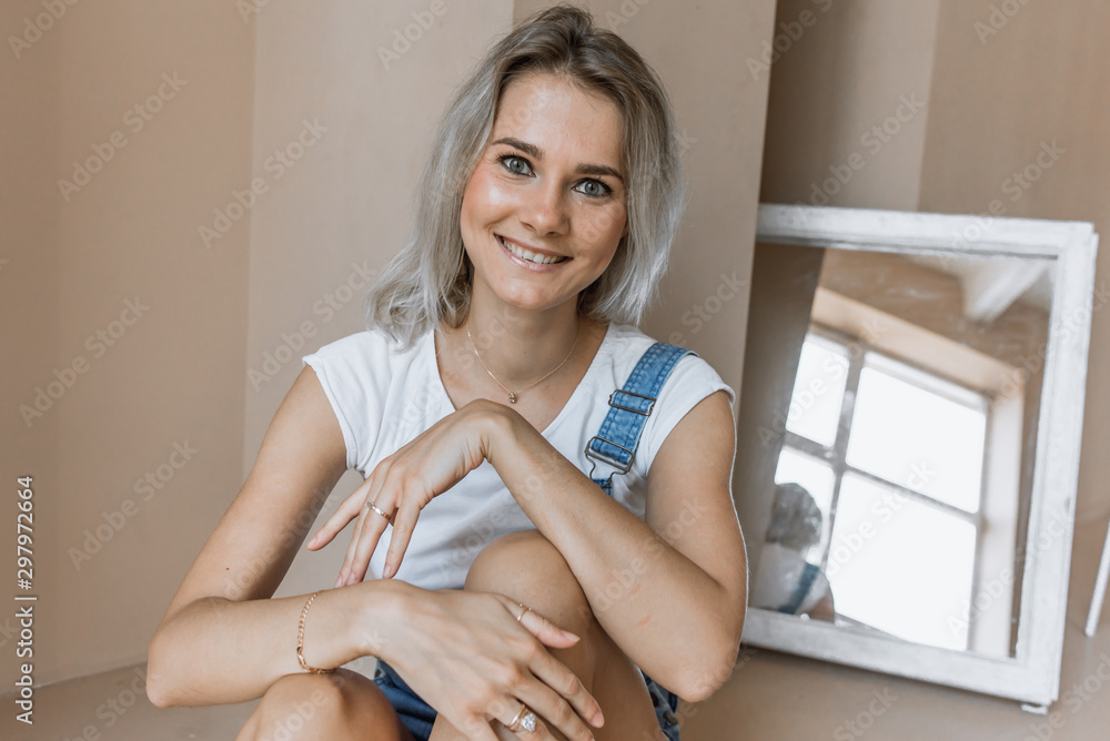 young pretty emotional and seductive girl in denim shorts is in a large spacious room with large windows and sits on the floor young pretty emotional and seductive girl in denim shorts is in a large spacious room with large windows and sits on the floor