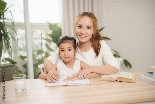 Mother teaching daughter how to write.