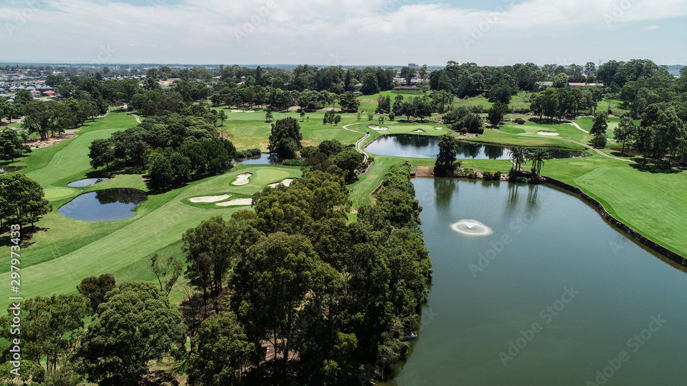 Aerial drone view Golf course fairway, water hazards, fountain, green with sand bunkers surrounded by trees