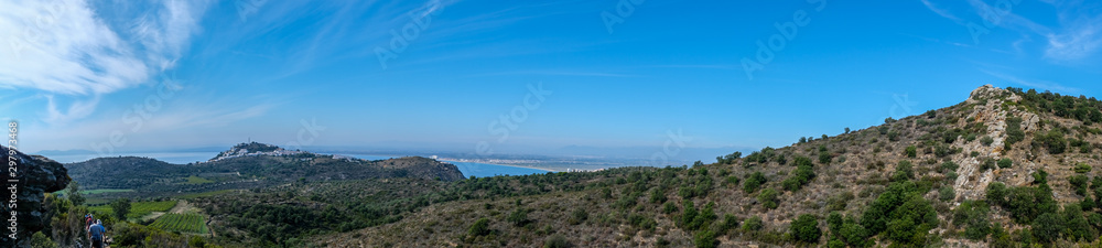 Mountain landscape in Roses, Catalunya, Spain. Mountain covered with green grass and shrubs on cloudy blue sky and sea background. Panoramic view, natural background.