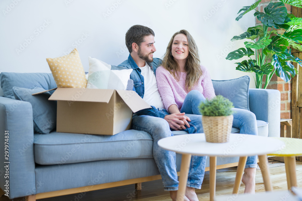 Young couple in love hugging sitting on the sofa very happy moving to a new home Young couple in love hugging sitting on the sofa very happy moving to a new home