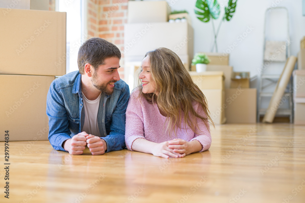 Young beautiful couple in love relaxing lying on the floor together with cardboard boxes around for moving to a new house Young beautiful couple in love relaxing lying on the floor together with cardboard boxes around for moving to a new house