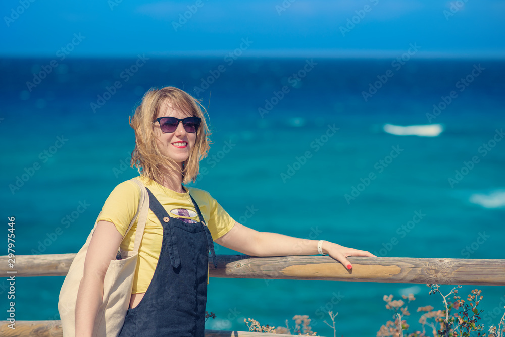Φωτογραφία The portrait of young European woman in sunglasses against picturesque seascape