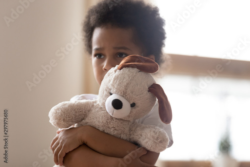 Hurt small biracial boy hold toy feeling lonely photo