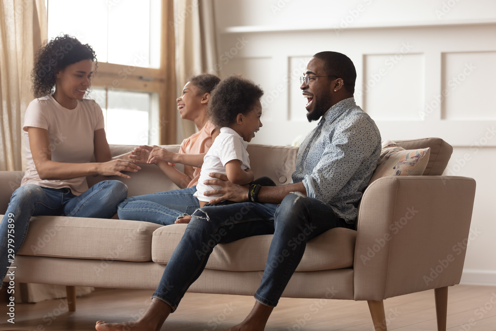 Overjoyed black family with kids play together on couch Overjoyed black family with kids play together on couch