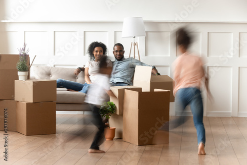 Young parents watch small kids running on moving day