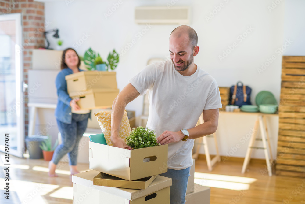 Young couple moving to new apartment, handsome man moving cardboard boxes and smiling happy Young couple moving to new apartment, handsome man moving cardboard boxes and smiling happy
