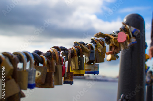 Extreme close up of multicolored padlocks (or locks) in the fence of a bridge in Liverpool dock, England, United Kingdom