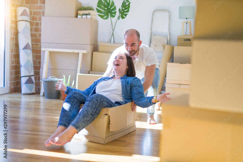 Funny and crazy couple having fun riding a cardboad box as a car, smiling happy and laughing at new home Funny and crazy couple having fun riding a cardboad box as a car, smiling happy and laughing at new home
