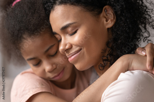 Close up of loving black mom hugging cuddling with daughter