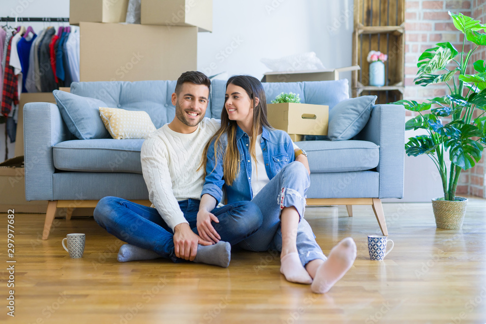 Young beautiful couple sitting on the floor of new apartment, smiling in love happy for moving to a new home Young beautiful couple sitting on the floor of new apartment, smiling in love happy for moving to a new home