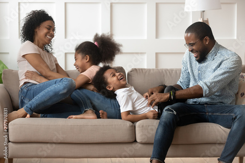 Playful black parents have fun playing with kids at home