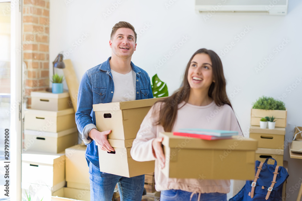 Beautiful young couple smiling in love holding cardboard boxes, happy for moving to a new home Beautiful young couple smiling in love holding cardboard boxes, happy for moving to a new home